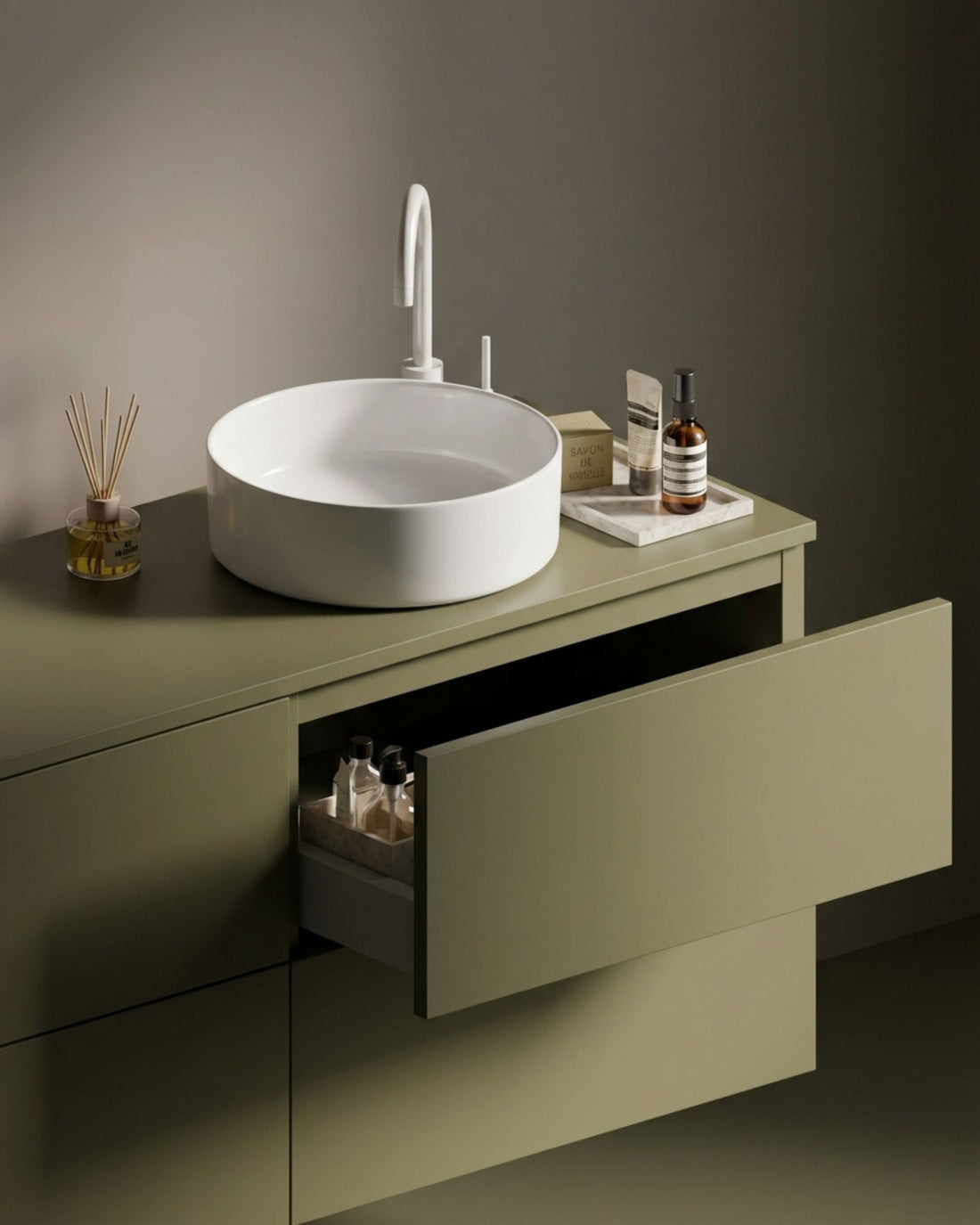 Meuble de salle de bain kaki, tiroir ouvert, robinetterie blanche